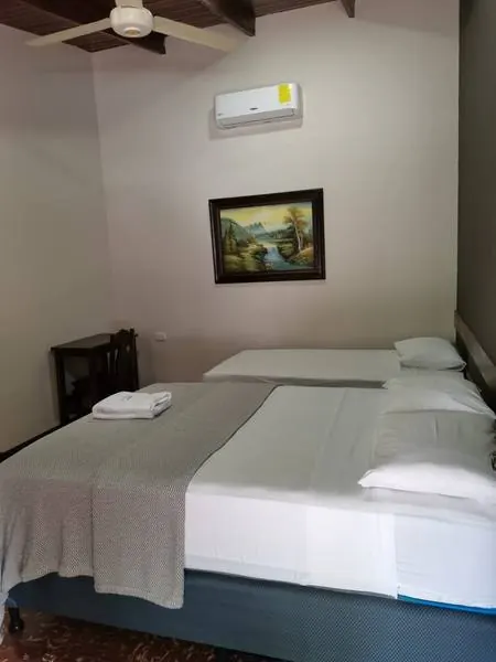 Habitación con una cama doble, una sencilla y aire acondicionado